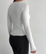 Close-up of bow accents on white knit top neckline