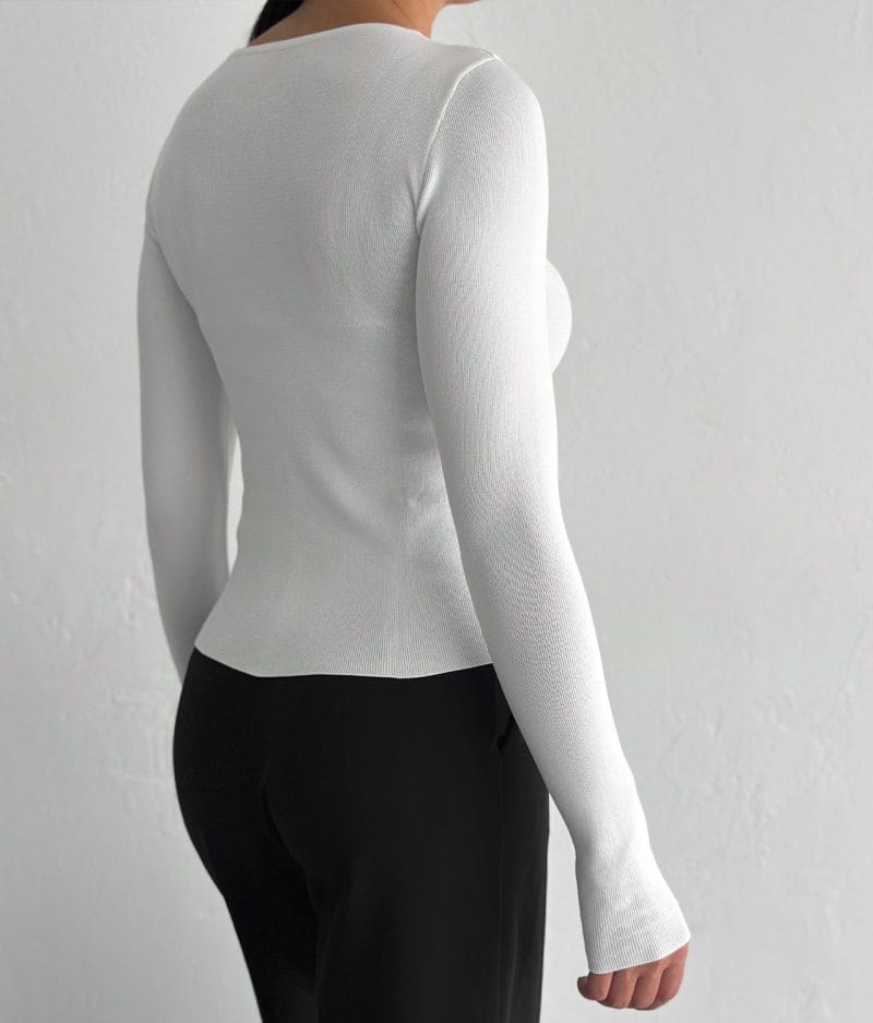 Close-up of bow accents on white knit top neckline