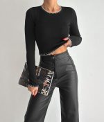 Black long sleeve knit top featuring elegant white contrast stitching details for wholesale buyers.