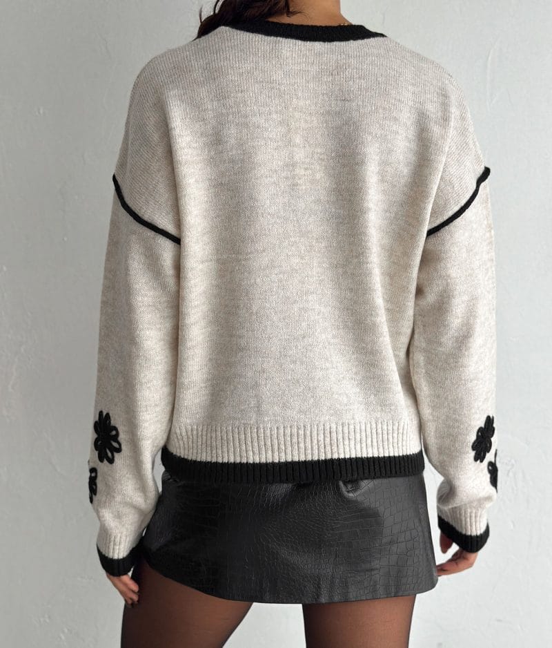 Ribbed hem knit pullover in beige with black floral sleeve design