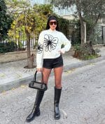 White oversized sweater styled with black shorts and sunglasses