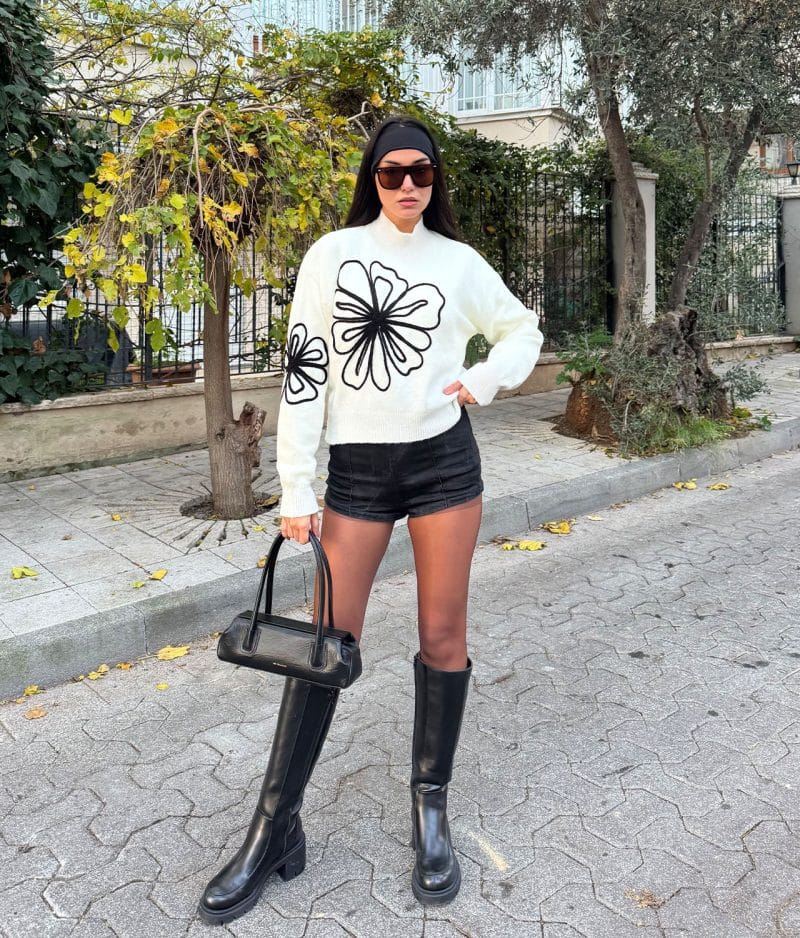 White oversized sweater styled with black shorts and sunglasses
